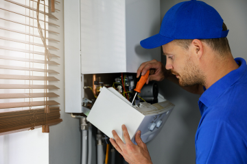 Engineer examining the control panel on a gas boiler for a residential central heating system