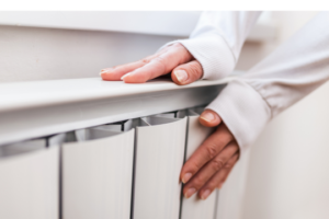 Female hand touching a white radiator